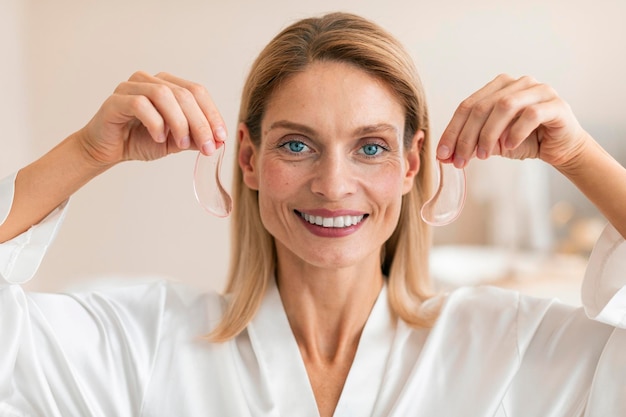 Photo modern cosmetology and antifatigue patches under eyes happy mature woman holding hydrogel patches in hands
