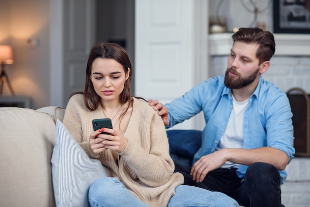 Coppia moderna a casa. uomo e donna si sono concentrati sulla messaggistica con gli smartphone, ignorandosi a vicenda e trascorrendo del tempo sui social media.