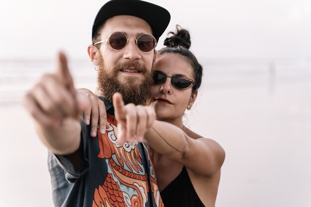 Modern couple with tattoos and piercings pointing