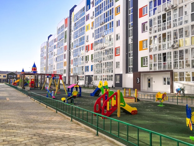 다채로운 놀이터가 있는 주거용 고층 건물의 현대적인 안뜰입니다. 건설 및 부동산.