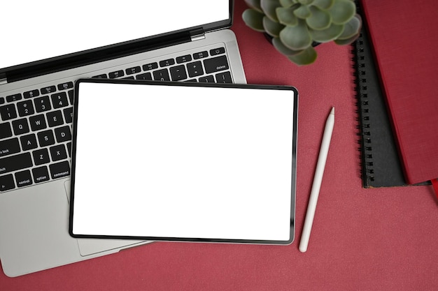 Modern creatief bureau bovenaanzicht met digitale tablet op een laptop op rode tafel