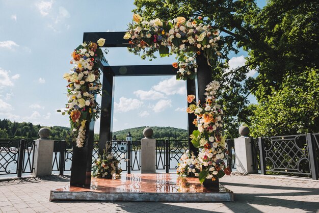 Modern creative black wedding arch with different flowers and leaves outside