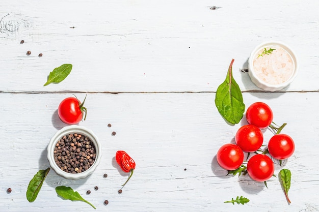 Modern culinary background with cherry tomatoes spices and herbs White wooden boards