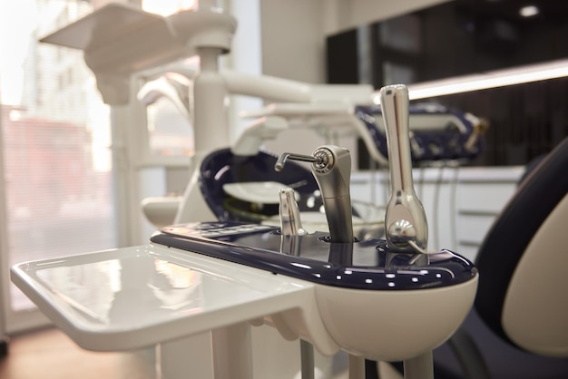 Фото Современный стоматологический стул и другие аксессуары, используемые стоматологами в синем медицинском свете
