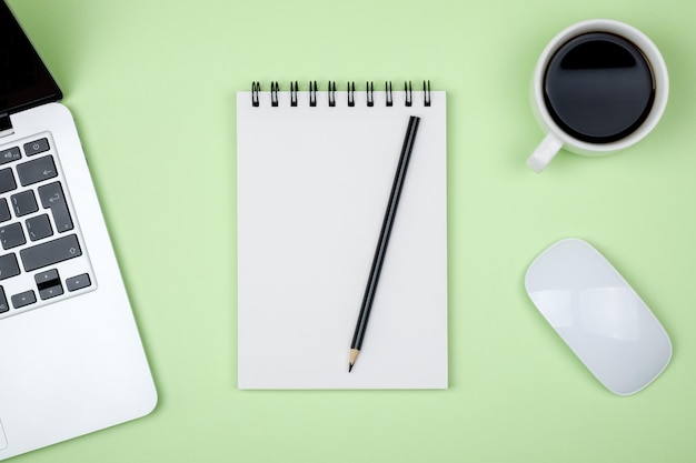 Modern designer office desk table with blank notebook page laptop computer and cup of coffee