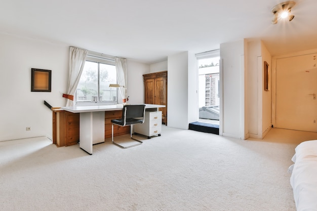 Modern desk and chair located in spacious home office with
white walls in light house