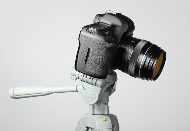 Modern digital camera with a tripod on gray table