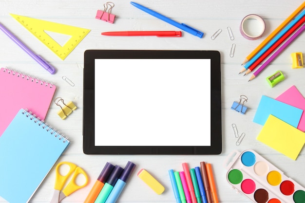 Modern digital tablet and school stationery on a colored background top view