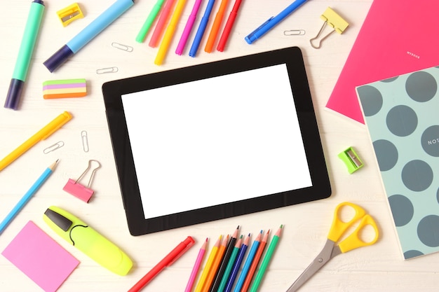 Modern digital tablet and school stationery on a colored background top view