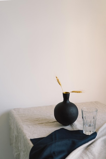 Modern dining table setting A beautiful black vase with a linen napkin on the table Only natural materials earthenware linen textiles dried flowers