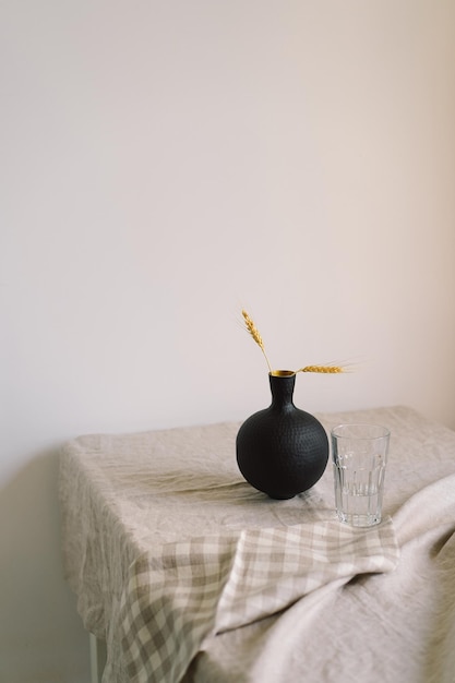 Modern dining table setting A beautiful black vase with a linen napkin on the table Only natural materials earthenware linen textiles dried flowers