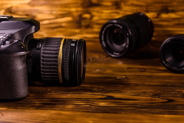 Modern dslr camera and lenses on rustic wooden table