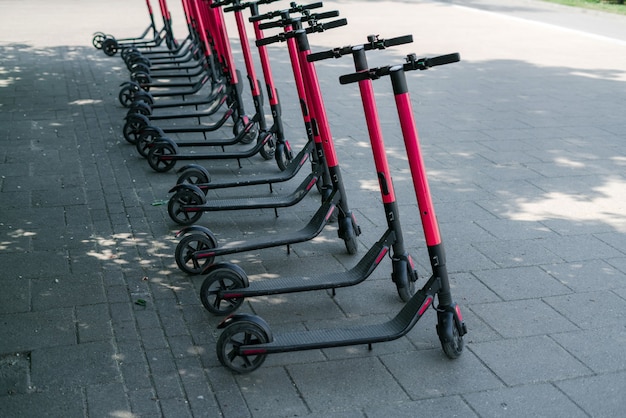 Modern eco electric city scooters for rent outdoors on the sidewalk.