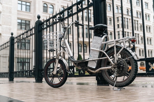 현대적인 전기 자전거가 비는 도시 거리에 주차되어 있습니다. 자전거는 화물 칸으로 장착되어 있으며 도시 풍경 속에서 효율적인 배달 서비스를 위해 적합합니다.