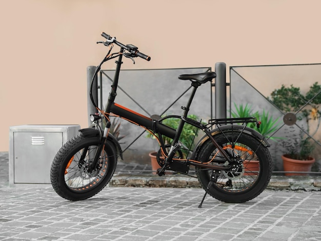 Современный электрический велосипед возле черного металлического забора на открытом воздухе