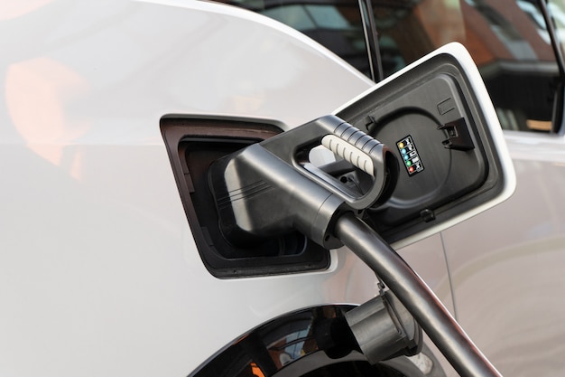 A modern electric car connected to a power supply unit charges the batteries at a fast charging station