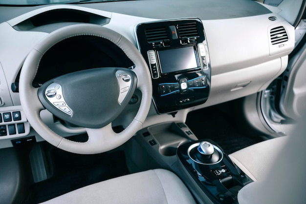 Modern electric car. Modern white car interior, leather steering wheel, climate control, navigation.