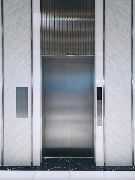 Modern elevator or lift doors made of metal closed in building\
with lighting