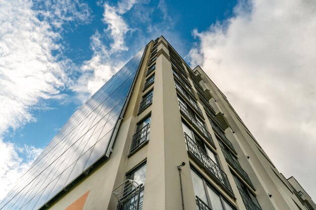 A modern energyefficient building against the background of clouds Multistorey residential building with solar panels on the wall Renewable energy sources in the city