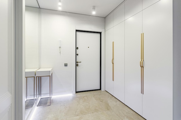 Modern entrance hall in light colors with interior doors in white and gold