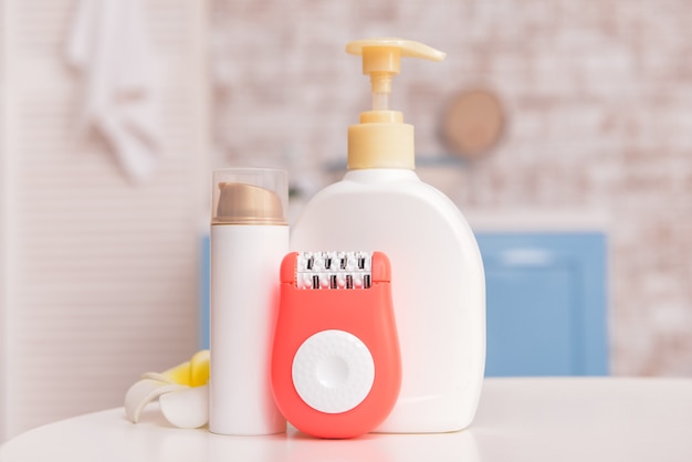 Modern epilator with cosmetics on table in bathroom