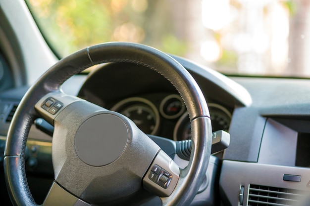 Modern expensive car black luxurious interior. Steering wheel, dashboard, windshield and mirror. Transportation, design, modern technology concept.