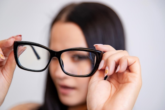 Modern eyeglasses with black frame in woman's hands Eye care and the choice the means to improve vision