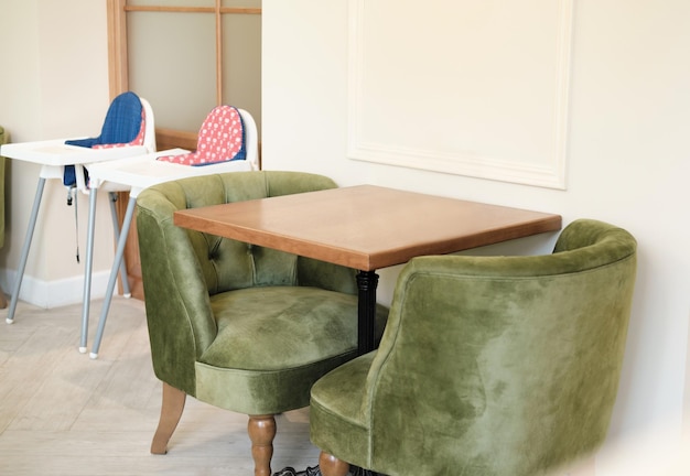 Modern family cafe interior a table with green soft upholstered
chairs and baby seats place for family dining and time spending
together elegant and comfortable place