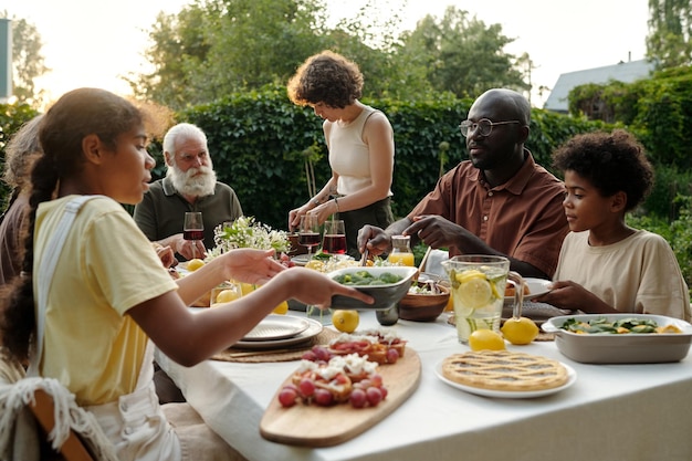 Modern family of kids their intercultural parents and grandparents by dinner