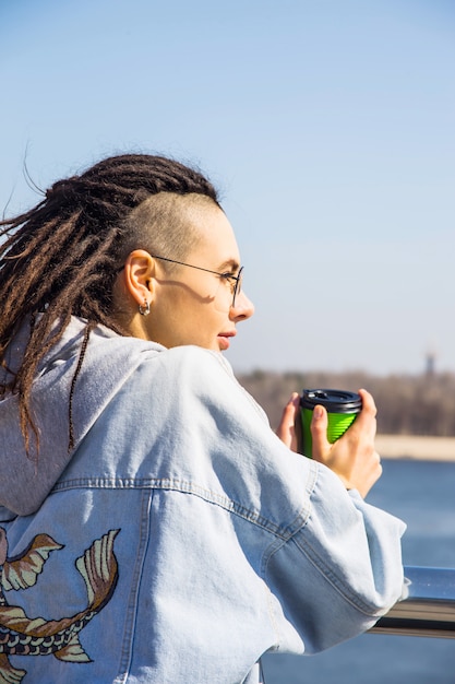 Modern fashionable beautiful girl alone on a spring walk by the river