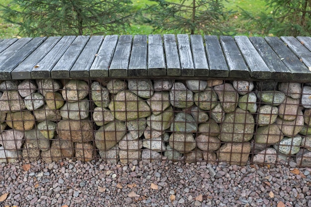 Panca da giardino moderna attorno al braciere in gabbione grigliato in acciaio zincato con pietre di granito