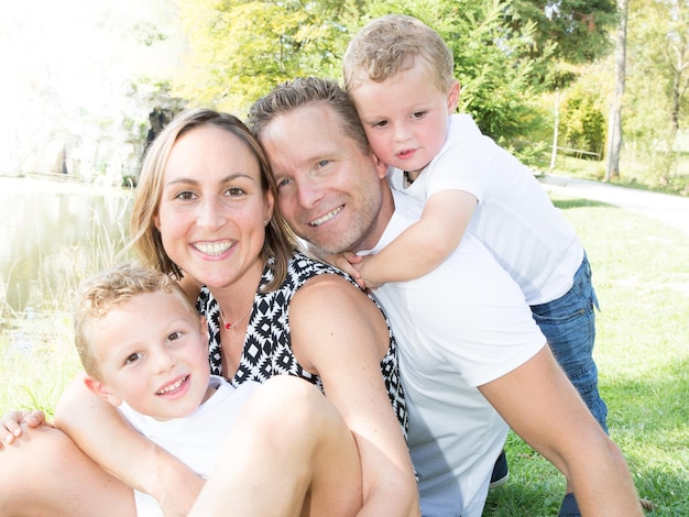 Modern gezin van vier met zoon, moeder en vader zitten op gras in de tuin