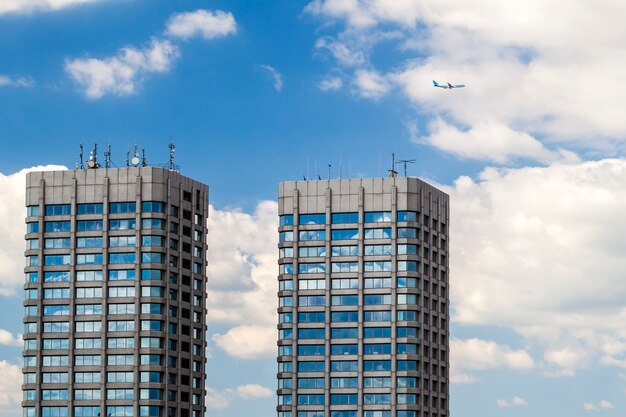 Modern glass and concrete skyscrapers and a plane in the sky