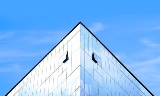 대칭 및 낮은 각도 보기에서 푸른 하늘 배경에 현대 유리 사무실 건물