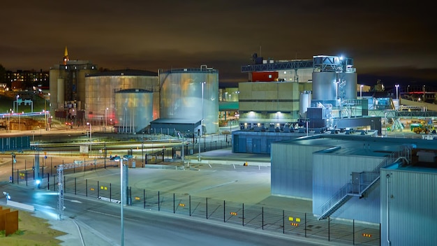 Modern grain terminal at night Metal tanks of elevator Graindrying complex construction Commercial grain or seed silos at seaport Steel storage for agricultural harvest