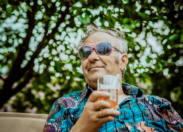 Il nonno moderno si gode la vita con un bicchiere di bevanda in mano