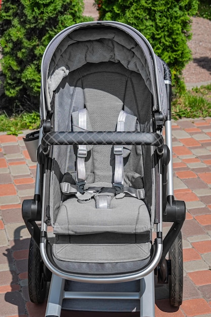 Modern gray baby carriage outside in the yard Safety belts fasteners