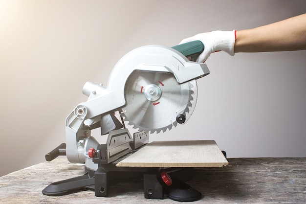 Modern green circular saw lies on wooden table. Circular saw blade wood with hard alloy insertions.