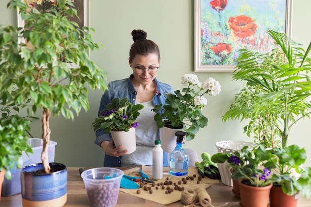 現代の緑の傾向アパートと鉢植えの植物のある家の造園鉢植えの植物の世話をする女性は、肥沃な趣味とアパートのレジャーホームガーデニングアーバンジャングルを植え替えます