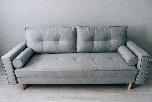 Modern grey sofa with wooden legs in the room