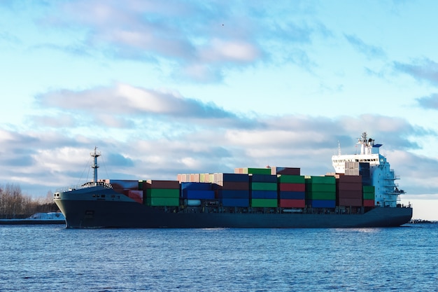 Modern grijs containerschip dat zich in stilstaand water beweegt