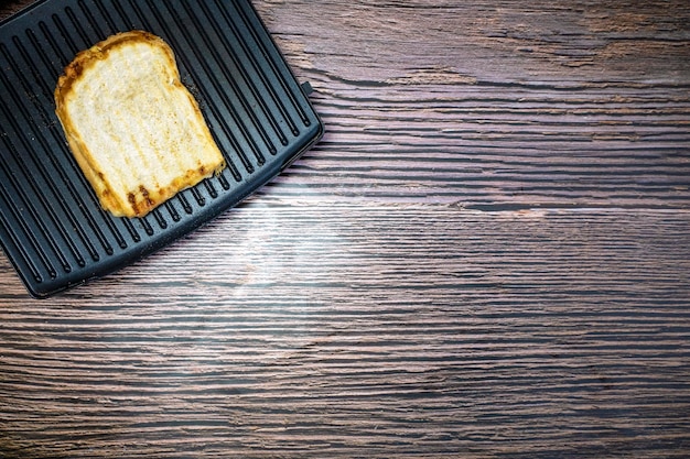 Modern grill maker with grilled cheese sandwich on wooden table top view copy space