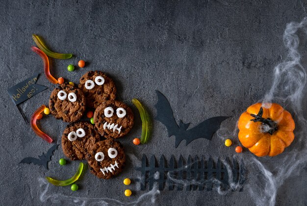 Sfondo moderno di halloween. biscotti di halloween. mostri divertenti fatti di biscotti con cioccolato sul tavolo