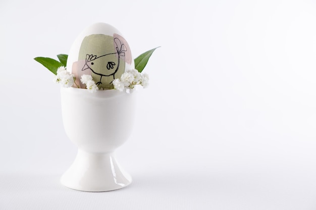 Modern hand painted easter egg in egg stand with flovers Minimal food and holiday concept