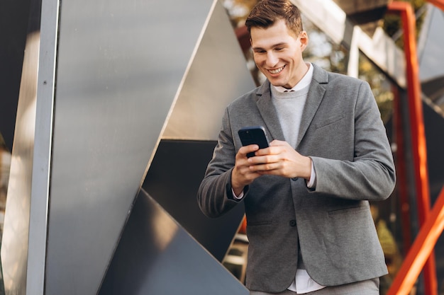 Modern handsome smiling man walking down the street and talking on the phone