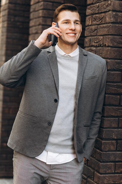 Modern handsome smiling man walking down the street and talking on the phone