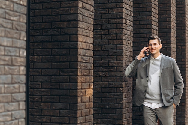 Modern handsome smiling man walking down the street and talking on the phone