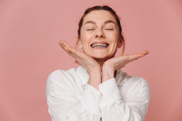 Modern happy woman showing smile with braces on pink background