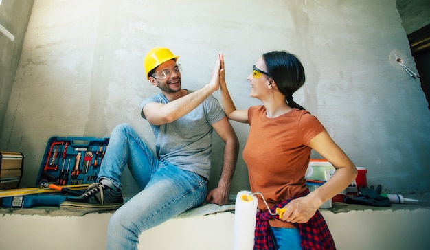 Modern happy young couple in love in casual clothes during new home repair or renovation of walls with a lot of tools for this