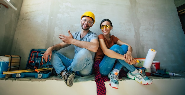 Modern happy young couple in love in casual clothes during new home repair or renovation of walls with a lot of tools for this